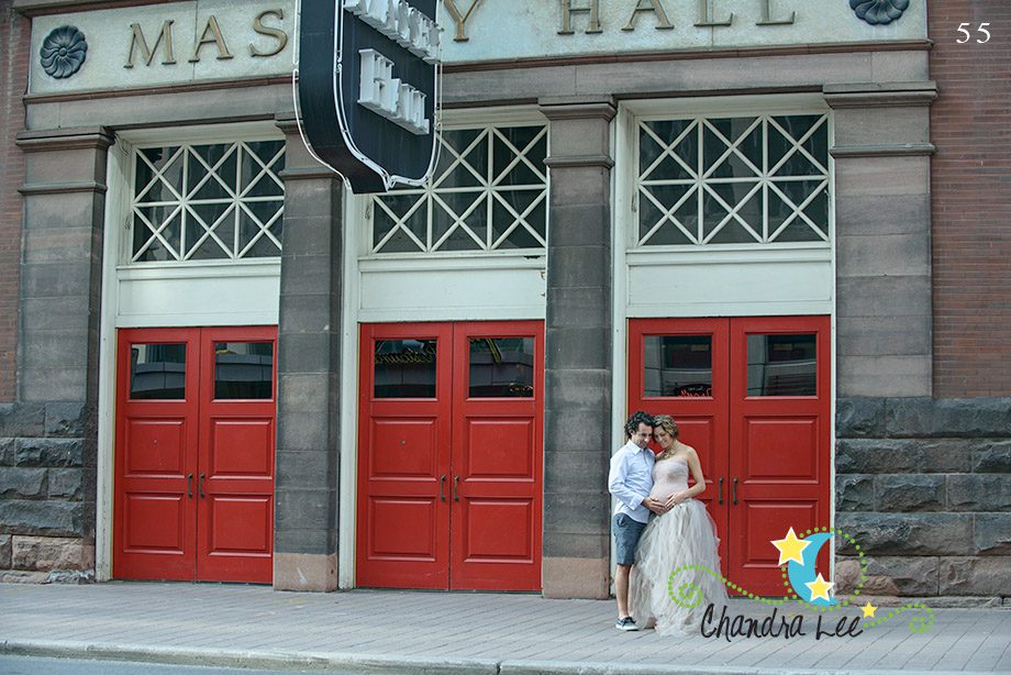 A couple stands outside a building with red doors labeled 
